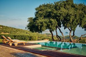 a swimming pool with two lounge chairs next to at Wild Oak Estate - Stone Villa with Sea Views , by ZanteWize in Argassi