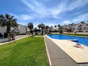 una piscina en un patio con palmeras y casas en Nice Ground Floor Apartment with Communal Pool in Los Dolses LD279, en Orihuela