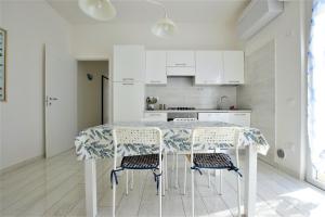 サン·ヴィンチェンツォにあるColombo apartment, fronte spiaggiaの白いキッチン(テーブル、椅子付)