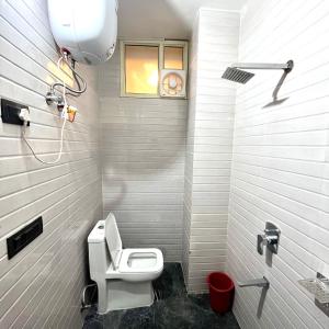 a white bathroom with a toilet and a window at Hotel Shanti Residency in Katra
