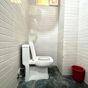 a bathroom with a toilet and a red trash can at Hotel Shanti Residency in Katra +2 photos