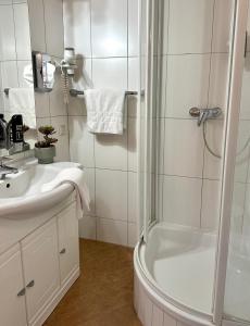 uma casa de banho branca com um chuveiro e um lavatório. em Landhotel Stegersbach em Stegersbach