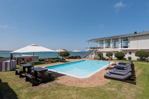 a swimming pool with chairs and umbrellas next to a building at Saldanha Bay Hotel in Saldanha