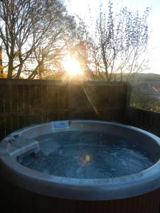 un jacuzzi con la puesta de sol en el fondo en Silver Birch Lodge with Hot Tub, en Cupar