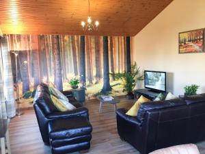 Sala de estar con 2 sofás de cuero y TV en Silver Birch Lodge with Hot Tub, en Cupar