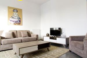 ein Wohnzimmer mit einem Sofa und einem TV in der Unterkunft Cheverus - Appartement 1 chambre avec ascenseur et Parking in Bordeaux