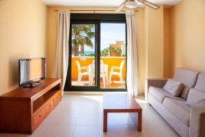 a living room with a couch and a tv at Apartamentos Playamarina in Isla Canela
