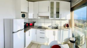 eine Küche mit weißen Schränken und einem weißen Kühlschrank in der Unterkunft Licorne G14 in Cannes
