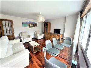 uma sala de estar com mobiliário branco e uma mesa de vidro em playa Santa Cristina em Oleiros