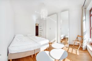 a white bedroom with a large bed and two white chairs at Apartamenty Sun & Snow Kamienice Nad Motławą in Gdańsk