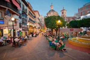 a group of people sitting at tables on a city street at Centro Plaza Sardoy in Murcia