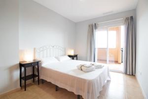 ein weißes Schlafzimmer mit einem Bett und einem Fenster in der Unterkunft Global Properties, Apartamento con terraza y piscina en la playa de Canet in Canet d'en Berenguer + 27 Fotos