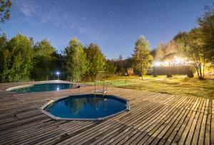 two pools on top of a wooden deck at night at Vortice Chile Eco-Lodge in Manzanar