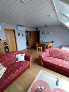 Rhede的住宿－Angelika Ferienwohnung，客厅配有两张红色的沙发和一张桌子