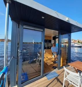 un uomo seduto sul ponte di una barca di Houseboat Deneb pływający domek a Ruciane-Nida