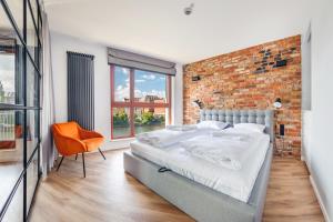 a bedroom with a large bed and a brick wall at Apartamenty Sun & Snow Waterlane Island z basenem in Gdańsk