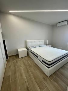 ein weißes Schlafzimmer mit einem Bett und Holzboden in der Unterkunft Appartamento esclusivo in Monaco in Beausoleil