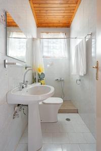 a white bathroom with a sink and a toilet at Salty Pebble House in Fiskardho