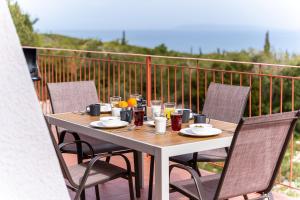 a table and chairs on a balcony with a table and drinks at Salty Pebble House in Fiskardo
