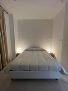 Cama blanca en habitación blanca con 2 lámparas en Appartamento La Fenice, en Génova