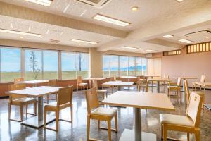 a dining room with tables and chairs and windows at Umino Hotel Hajime - former Umikaoru Yado Hotel New Matsumi in Beppu