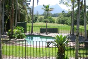 a fence around a pool with palm trees and mountains at The Bushranger Hideaway in Midginbil
