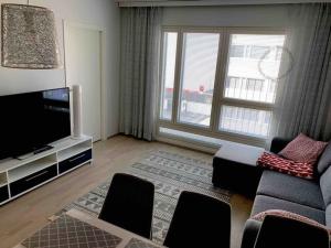 a living room with a couch and a tv at Uusi tilava kaksio Jyväskylän ydinkeskustassa 53 m2 in Jyväskylä