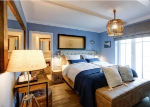 a blue bedroom with a bed and a lamp at Seventy Seven Beach Hotel in Timmendorfer Strand