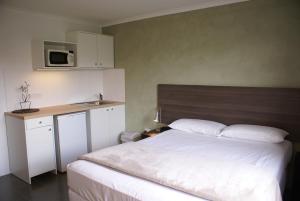 1 dormitorio con 1 cama y cocina con microondas en Mackay Motor Inn en Mackay