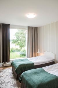 a hotel room with two beds and a window at Pehtoori 1 Hahkialan Kartanon vierastalon huoneisto in Hämeenlinna