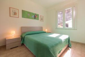 sypialnia z zielonym łóżkiem i oknem w obiekcie HelloElba Residenza Peducelli w mieście Capoliveri