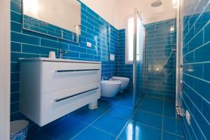 W wyłożonej niebieskimi kafelkami łazience znajduje się umywalka i toaleta. w obiekcie HelloElba Residenza Peducelli w mieście Capoliveri
