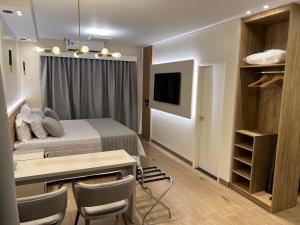 a bedroom with a bed and a desk with chairs at Ônix Hotel in Assis
