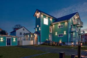 een groot groen huis met verlichting bij Seventy Seven Beach Hotel in Timmendorfer Strand