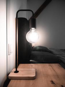 una lámpara en una mesa de madera junto a una cama en Dwupoziomowy Apartament Królowej Jadwigi 3, en Bydgoszcz