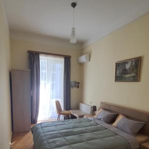 a bedroom with a bed and a chair and a window at Guesthouse Hillside in Tbilisi City