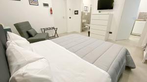 a white bedroom with a large bed and a chair at Palermo Central in Palermo