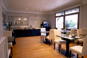 uma sala de jantar com mesas e cadeiras e uma cozinha em Le Divona em Divonne-les-Bains