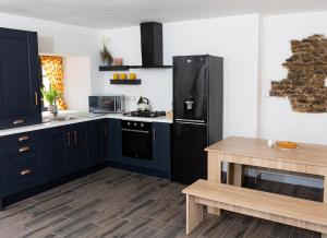 a kitchen with blue cabinets and a black refrigerator at Shannon Castle Holiday Cottages Type A 