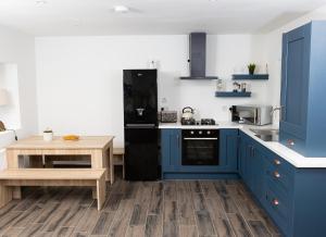 cocina con armarios azules y mesa de madera en Shannon Castle Holiday Cottages Type B, 