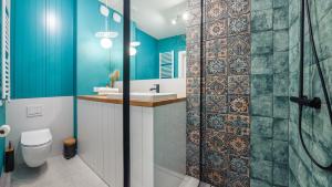 a bathroom with blue walls and a shower with a sink at Apartamenty Sun & Snow Aura 40 in Gdańsk