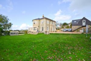 a large house with a green lawn in front of it at Hunter Heights Apartment at Clevelands in Wroxall