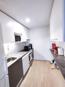cocina con armarios blancos y suelo de madera en Alvar, Tilava uusi kaksio ydinkeskustassa 53 m2, en Jyväskylä