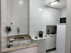 een witte keuken met een wastafel en een koelkast bij Boemia Carioca Lapa in Rio de Janeiro