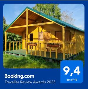 a rendering of a yellow house with a sign that reads travel review awards at Jaunveiti in Bernāti