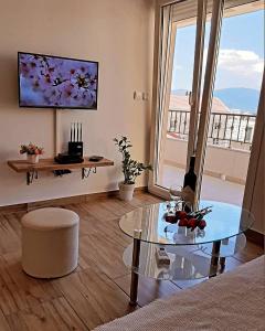 ein Wohnzimmer mit einem Glastisch und einem großen Fenster in der Unterkunft LightHouse Apartments in Tivat