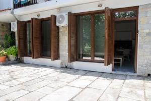 a house with wooden windows and a patio at Sirokos House in Agios Ioannis Pelio