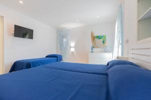 Pokój szpitalny z dwoma łóżkami z niebieską pościelą w obiekcie HelloElba Residenza Peducelli w mieście Capoliveri
