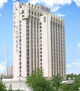 a tall white building with a sign on it at Avari Tower Karachi in Karachi