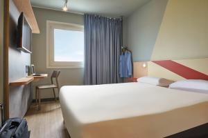 ein Hotelzimmer mit einem großen weißen Bett und einem Fenster in der Unterkunft ibis budget Paris Porte d'Aubervilliers in Aubervilliers